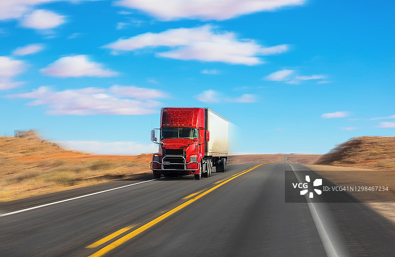 在犹他州乡村道路上运输货物的红色和白色半挂卡车图片素材