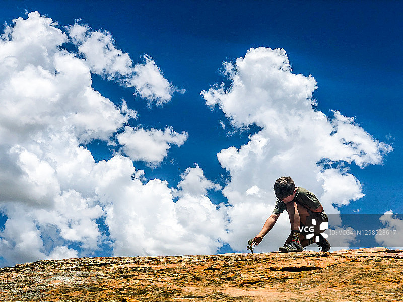 男孩呵护岩石中顽强生长的脆弱植物图片素材