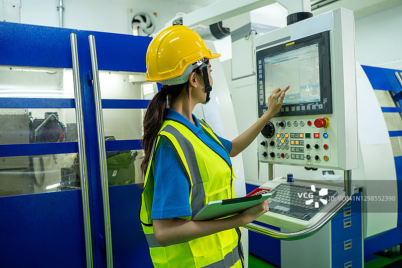 使用平板电脑操作数控铣床的女机械工程师图片素材