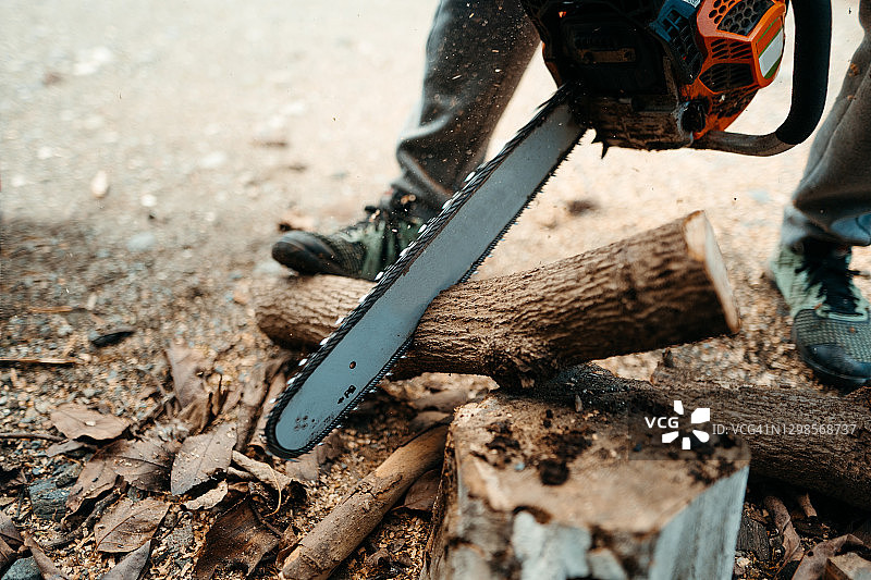 用油锯锯木柴的年轻男人图片素材