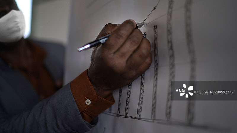 戴口罩的年长商人在办公室做演示图片素材