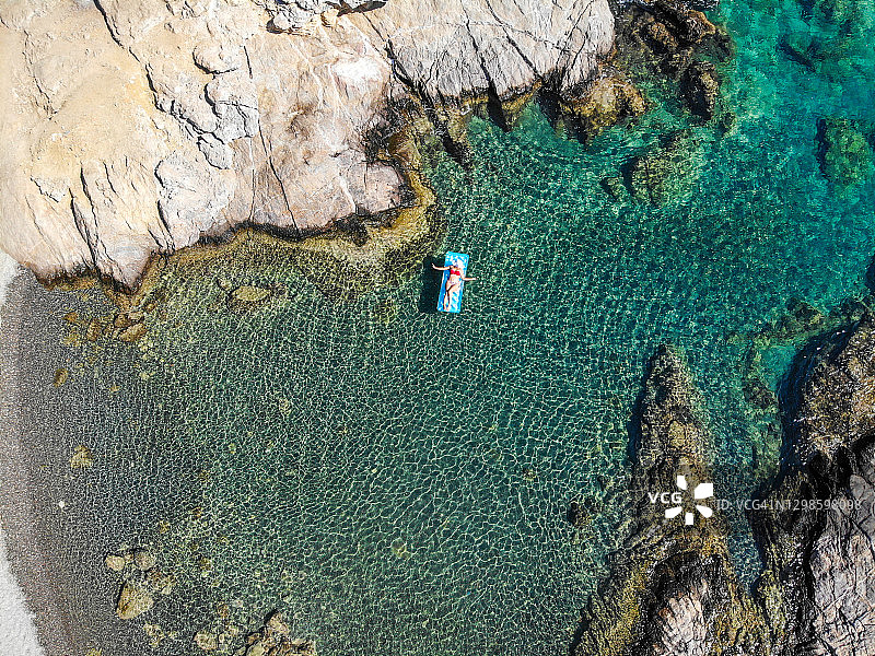 美丽的女人在海上的充气床垫上休息。图片素材