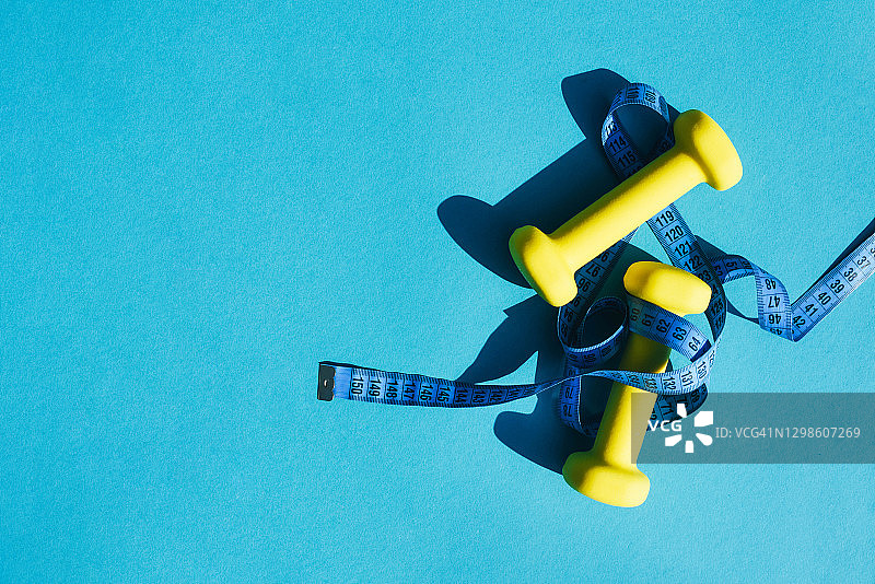 蓝色背景上用于体育锻炼的黄色壶铃和厘米图片素材