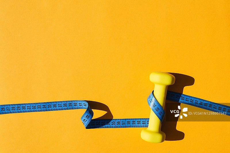 黄色背景上的运动健身用黄色壶铃和厘米图片素材