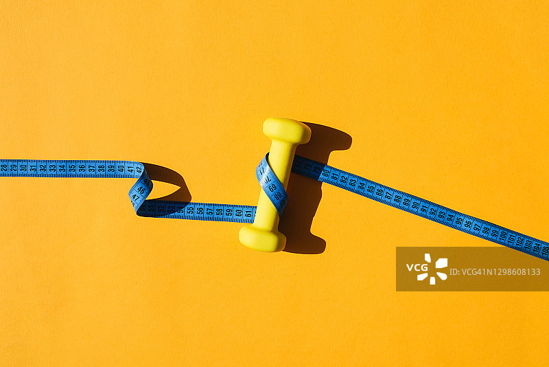 黄色背景上的运动健身用黄色壶铃和厘米图片素材