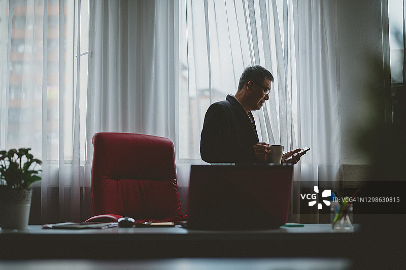 穿着休闲的商务人士在办公室里看手机图片素材