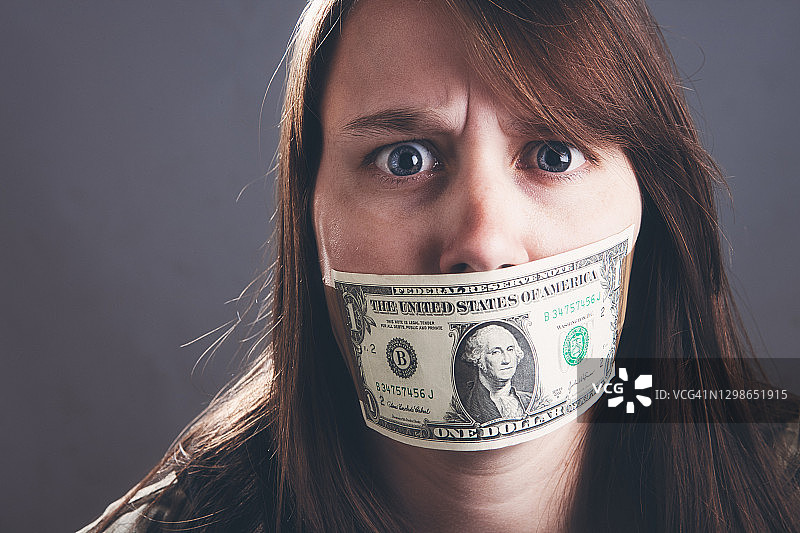 被美元堵住嘴，看起来既害怕又生气的年轻女人图片素材