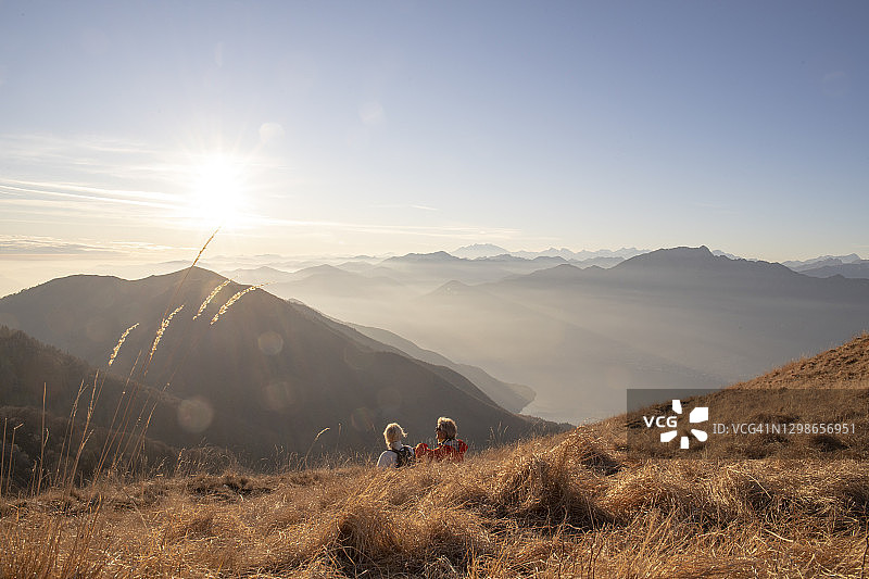 年长的徒步夫妇在早晨在长满草的山坡上放松身心图片素材