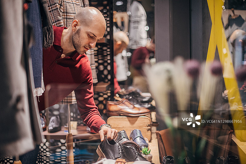 男人在时尚商店橱窗里挑选新鞋图片素材