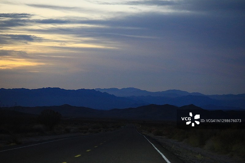 日落时沙漠中的笔直道路图片素材