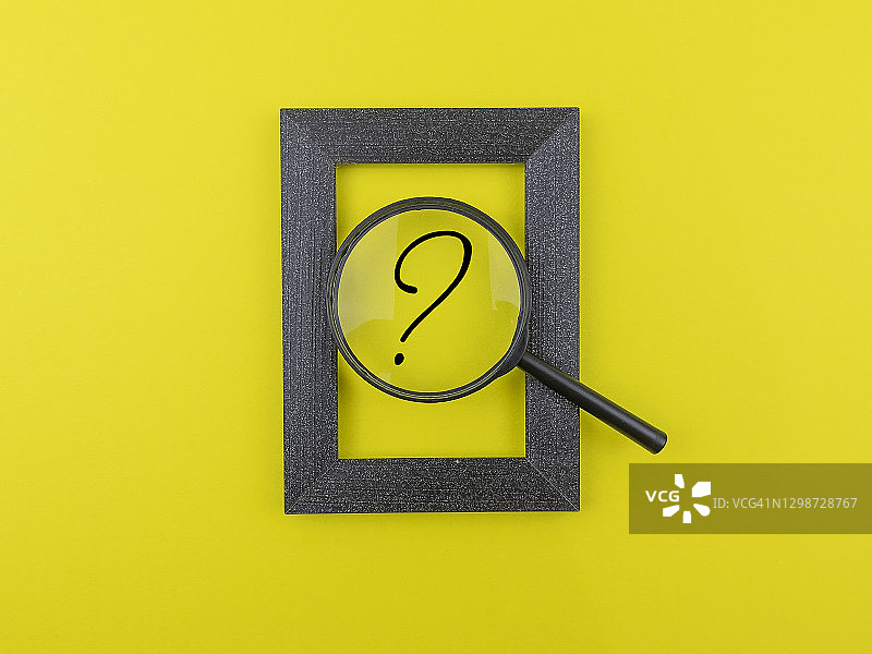 带有问号的放大镜，位于黄色背景的相框边框内图片素材