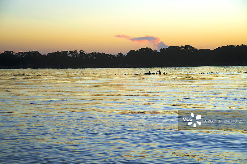 日落时分在奥里诺科河上划着库里亚拉船的瓦劳族家庭图片素材
