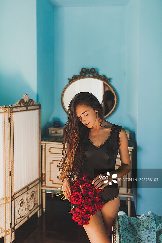 穿着性感内衣，手捧红玫瑰的年轻女子图片素材