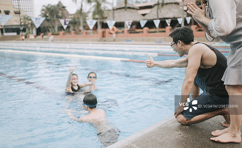 华人父母在泳池边鼓励孩子学习游泳图片素材