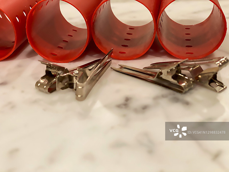 红色塑料卷发器和银色发夹图片素材