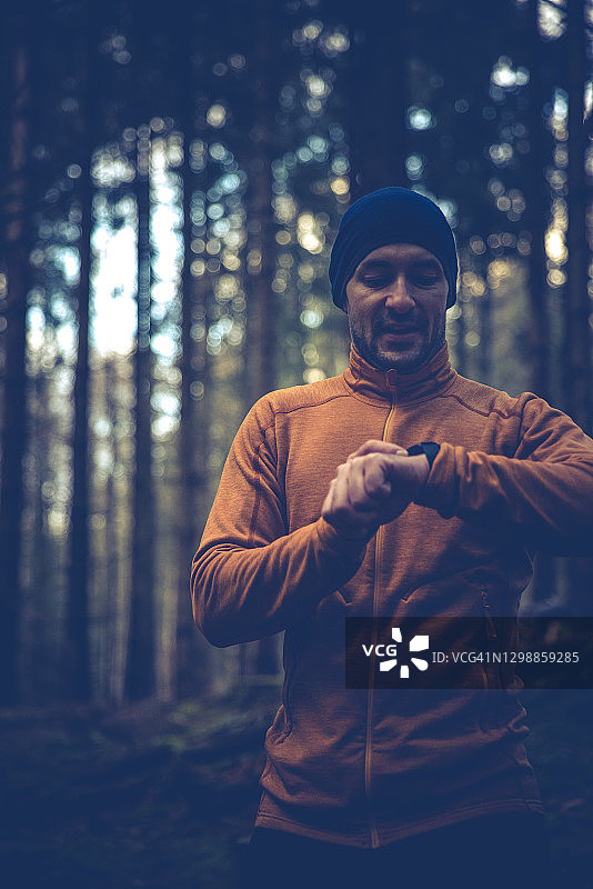 跑步者佩戴智能手表，身穿橙色外套图片素材