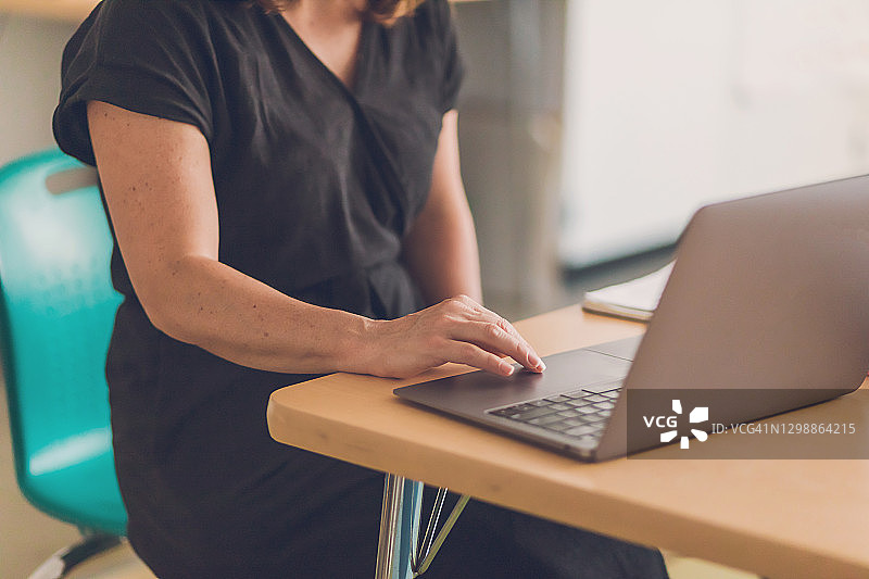 身穿黑色连衣裙的女子正在使用笔记本电脑图片素材