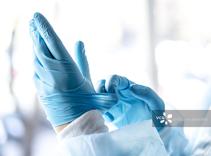 医学与外科主题：医生戴上蓝色防护手套图片素材