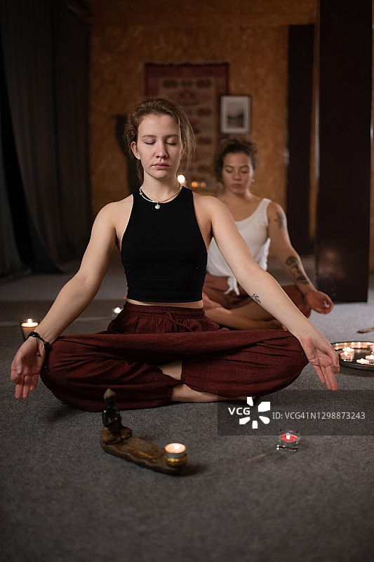 女教练在莲花坐姿女人旁冥想图片素材