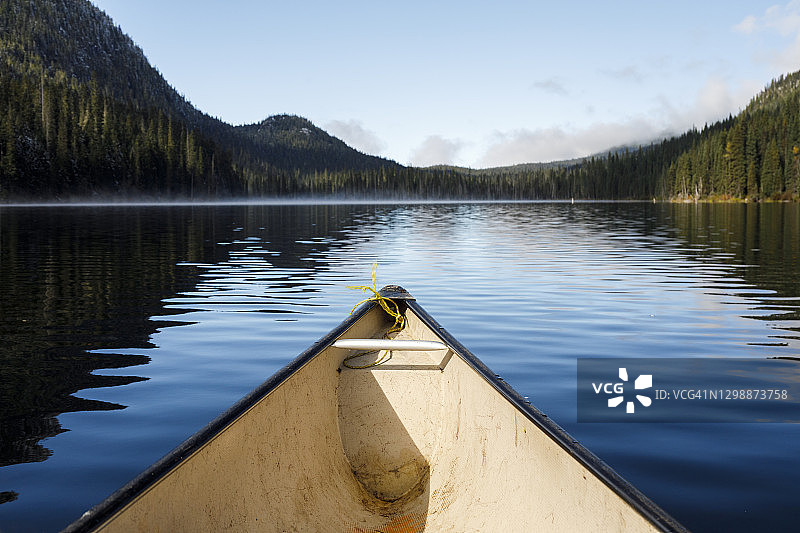 加拿大静谧湖面上森林环绕的独木舟船头图片素材