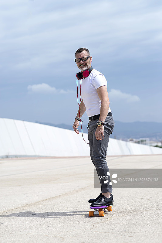 戴着耳机享受城市滑板的络腮胡男人图片素材