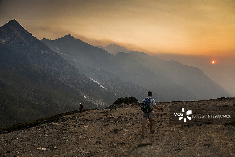 黎明时分，两名徒步旅行者攀登冰川峰顶图片素材