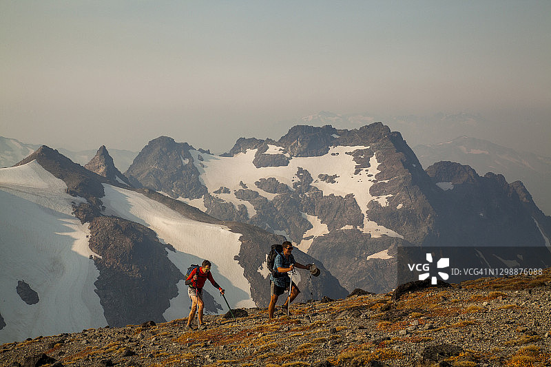 黎明时分，两名徒步旅行者攀登冰川峰顶图片素材