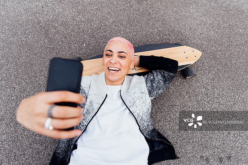 躺在滑板上玩手机的滑板手图片素材