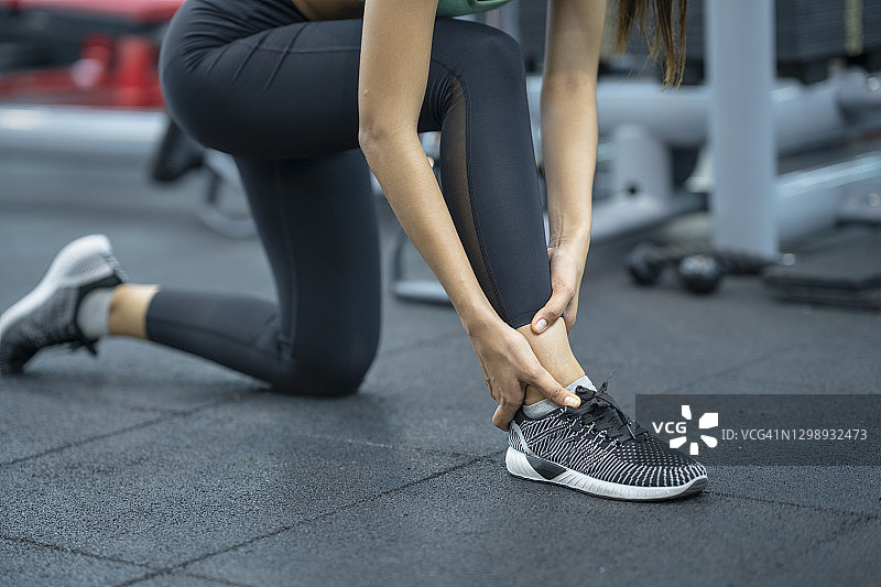 在健身房锻炼时脚踝疼痛的女人图片素材