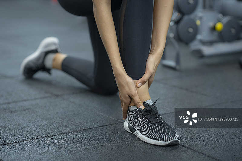 年轻的运动女性在健身房扭伤脚踝图片素材