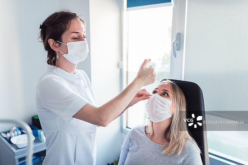 护士戴防护口罩检查病人的眼睛图片素材