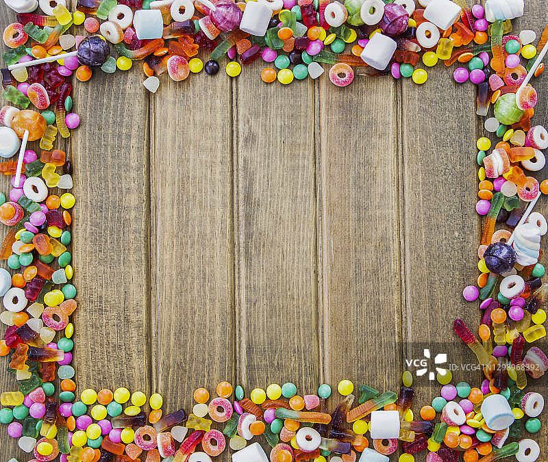 色彩缤纷的糖果，木制背景上的糖果边框图片素材