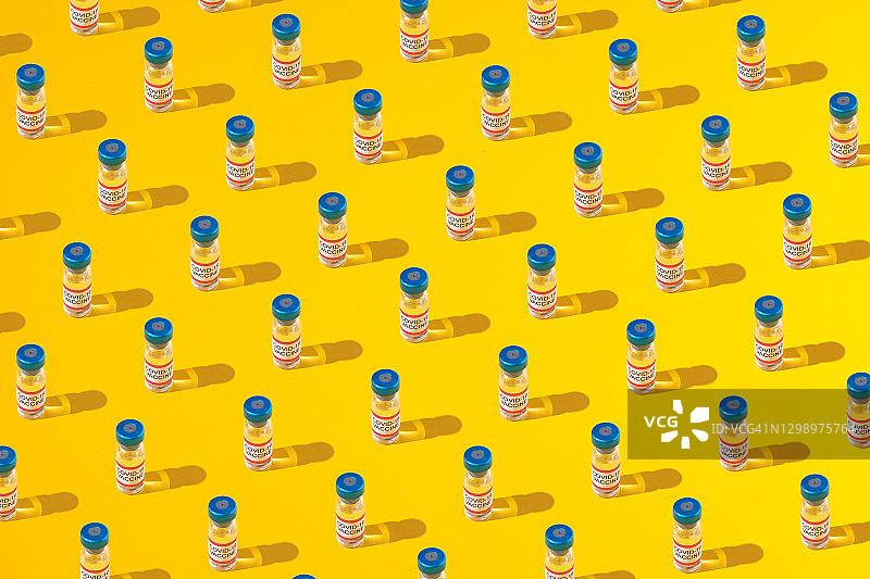 黄色背景上的新冠疫苗瓶图案图片素材