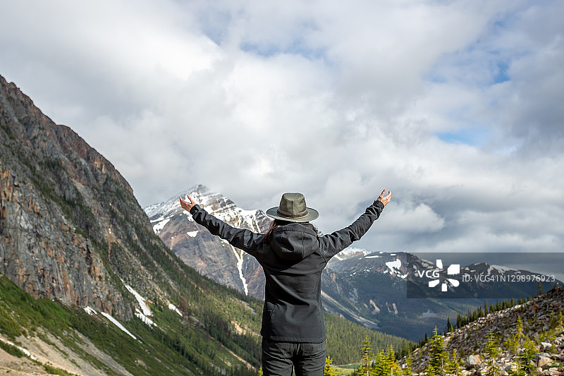 在加拿大阿尔伯塔省伊迪丝·卡维尔山举起双臂的年轻女子图片素材