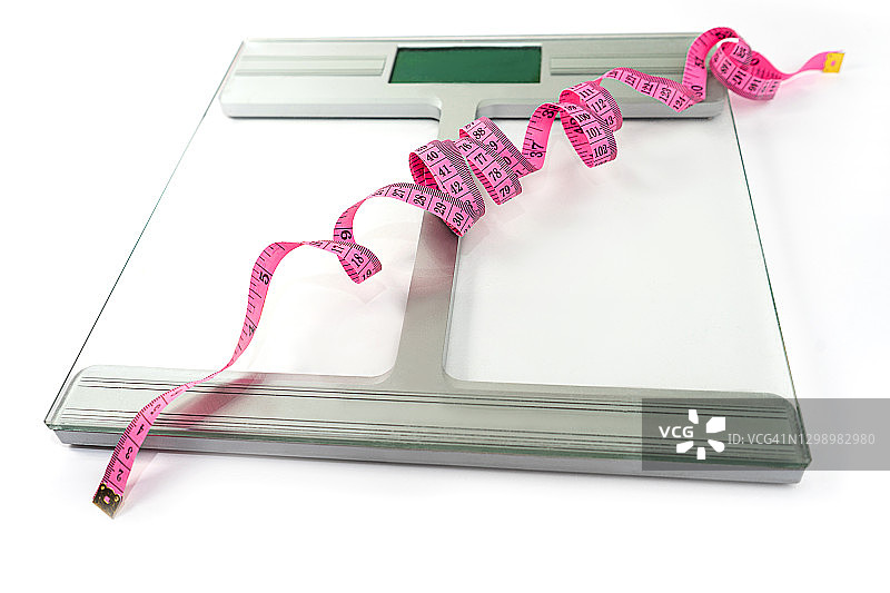 浅灰色背景上的带蓝色卷尺的体重秤图片素材