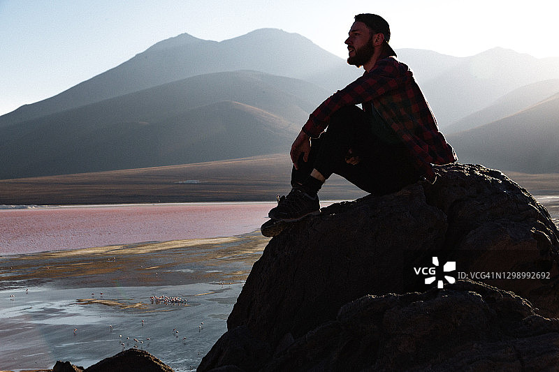 白人男子坐在玻利维亚高原科罗拉达泻湖旁欣赏风景图片素材
