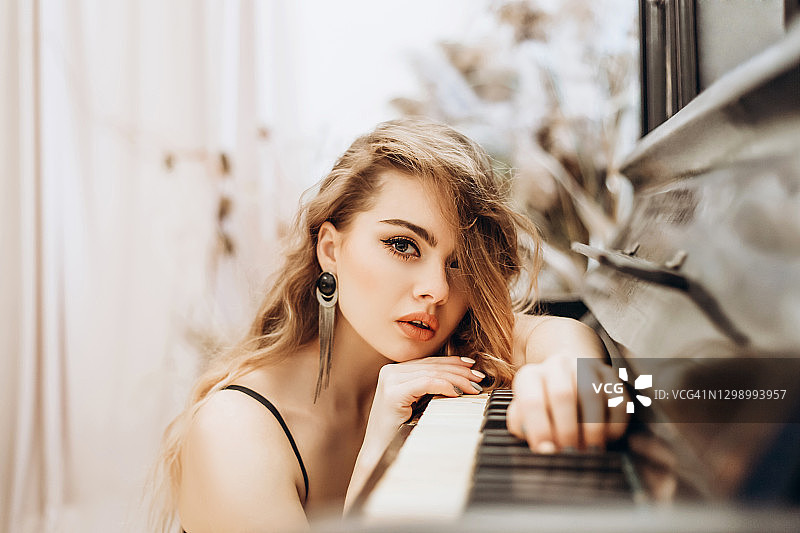 躺在钢琴键上的年轻金发女子图片素材