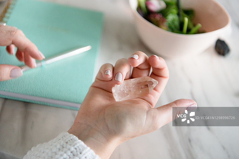 女人手持发光水晶，背景是笔记本图片素材