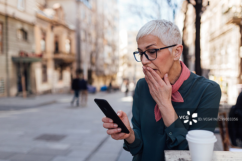 使用智能手机的灰发年长白人女性图片素材