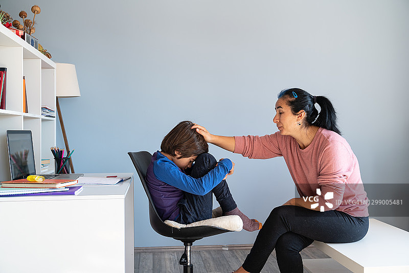 母亲与正在进行在线学习的厌学儿子交谈图片素材