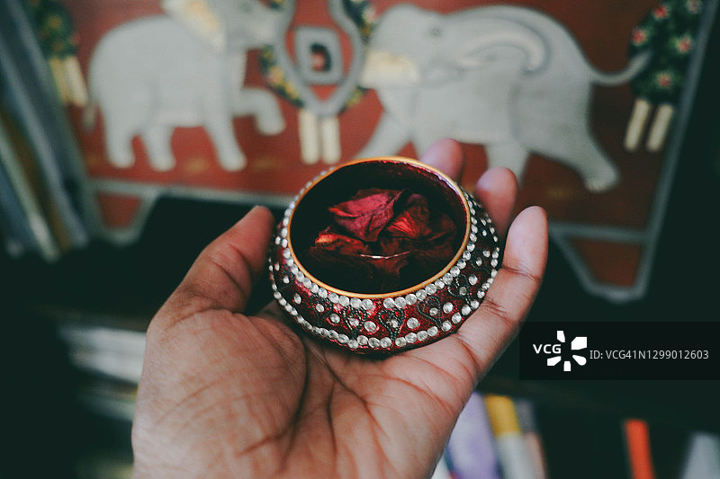 女人在小珠宝盒里拿着干玫瑰花瓣图片素材