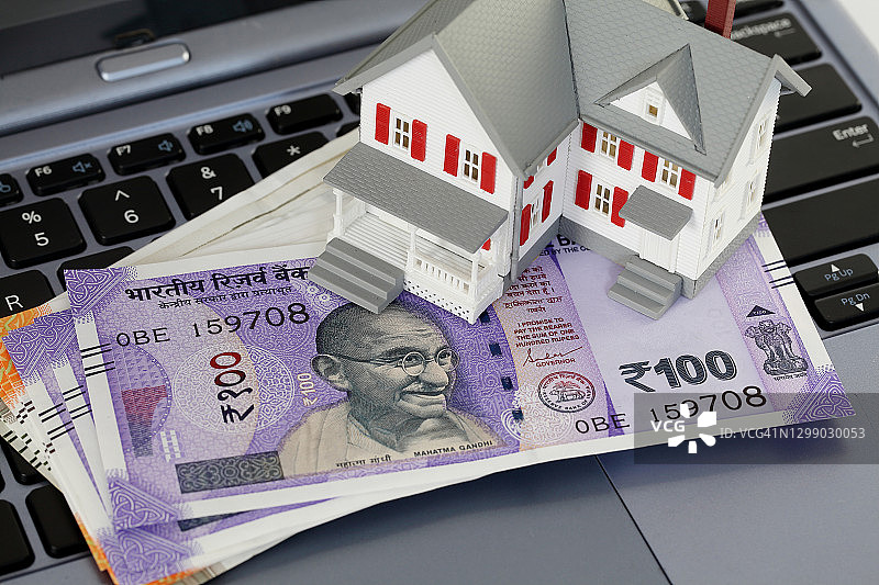 笔记本电脑键盘上的迷你房屋和货币图片素材
