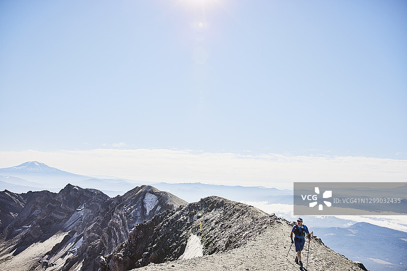 中年男人在圣海伦斯火山的山脊上徒步旅行，背景是亚当斯山图片素材