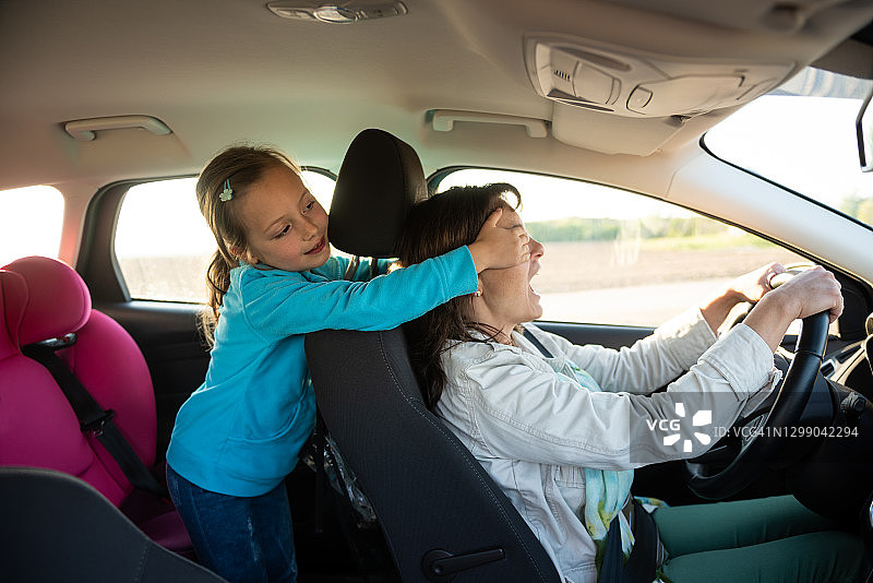 儿童在开车时蒙住妈妈的眼睛图片素材