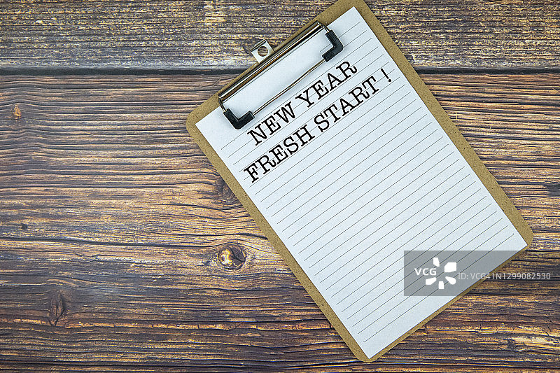 记事本上的新年新开始文字。木制背景。图片素材