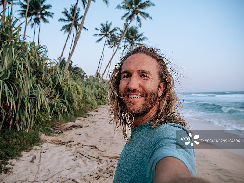 快乐的男人在日落时在海滩上自拍图片素材