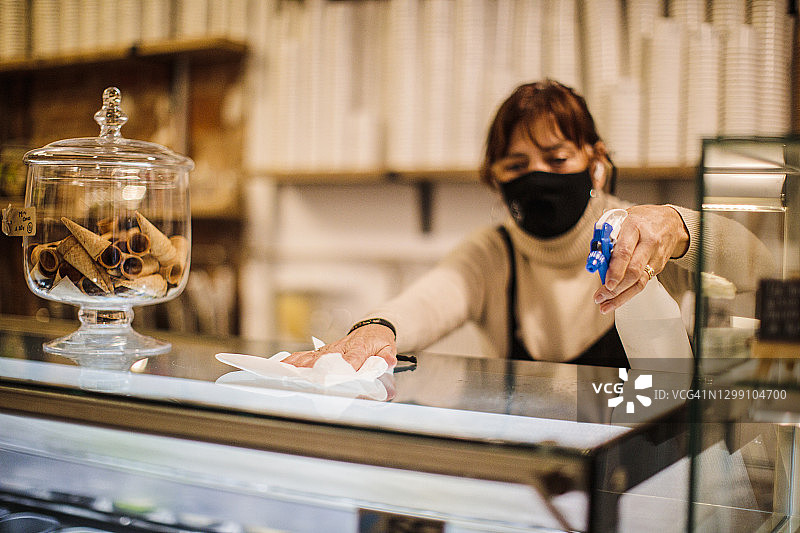 女服务员戴口罩清洁餐厅并消毒吧台图片素材