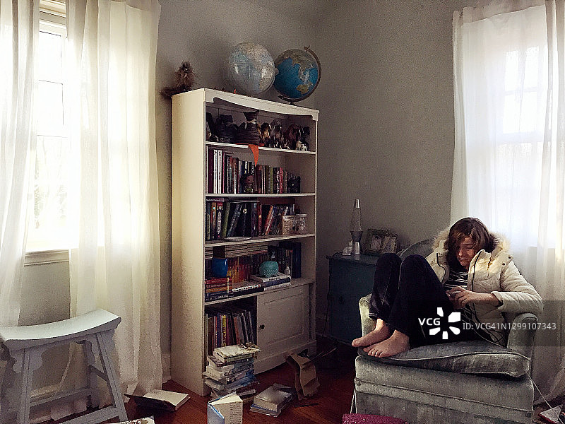 十几岁的女孩在她凌乱的房间里阅读图片素材