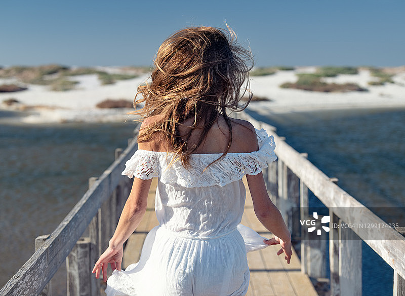 在意大利撒丁岛度假码头上跳跃的漂亮女人图片素材
