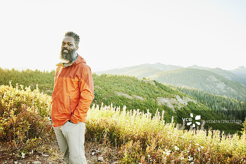 日落时分站在山脊上，背景是森林的微笑男人肖像图片素材